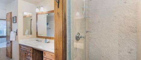 Une salle de bain avec une douche à parois de verre, des meubles en bois et un grand miroir.