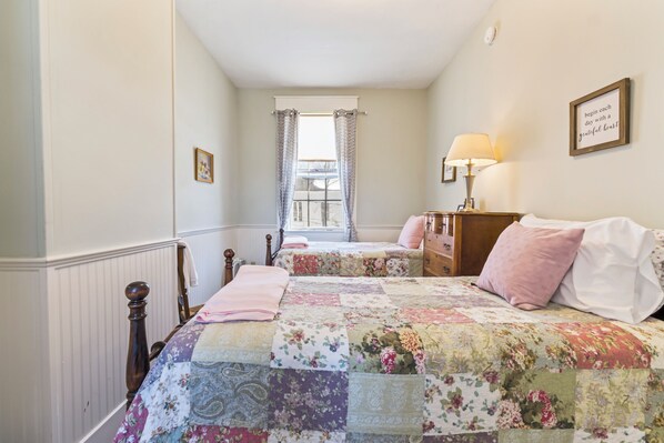 A bedroom with two beds, a window with curtains, a bedside table with a lamp, and a framed quote on the wall. - The Jeremiah Mason House B & B (Limerick)
