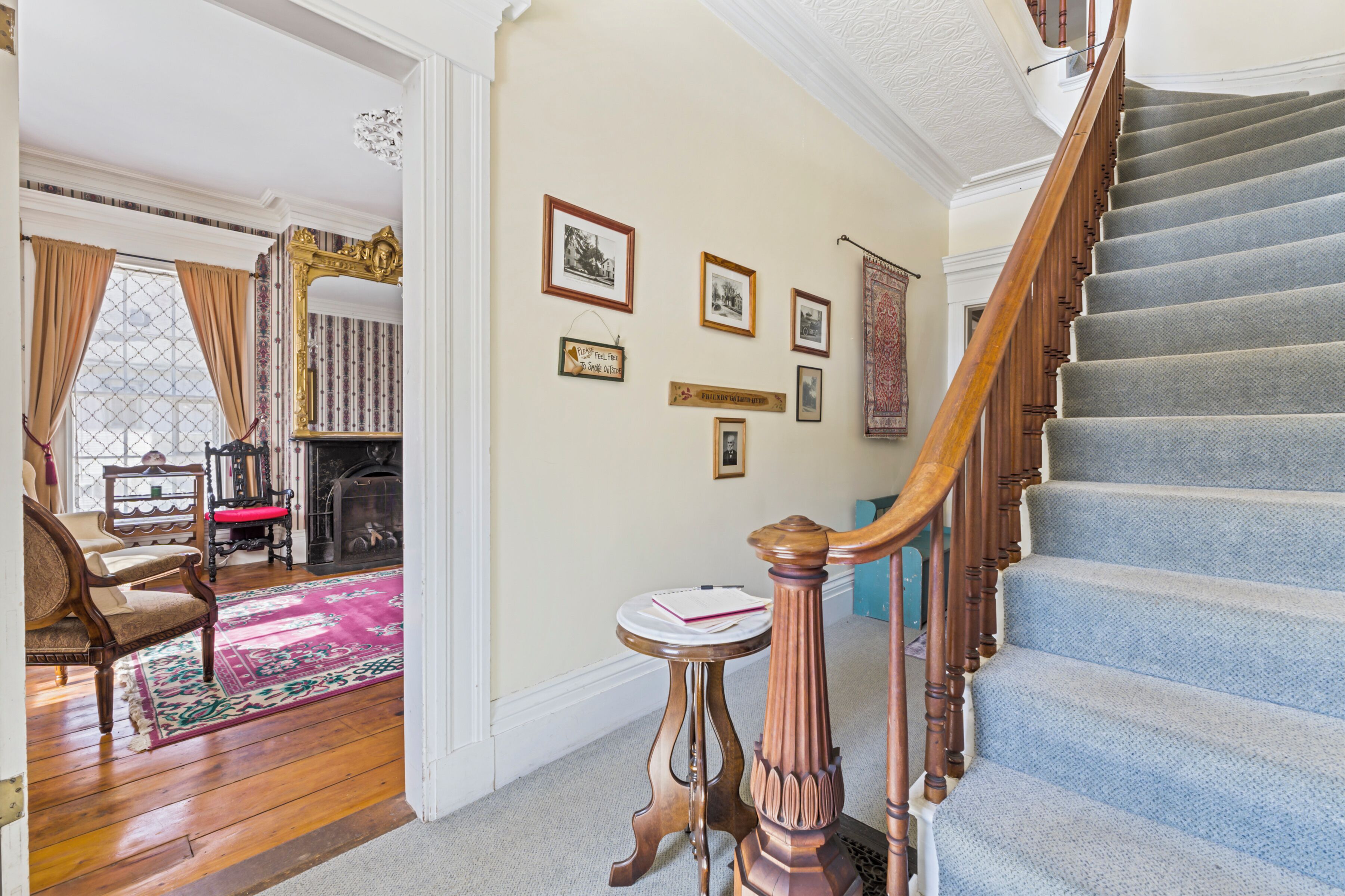 Un magnifique escalier avec une rampe en bois, un sol recouvert de moquette et un mur orné de tableaux encadrés.