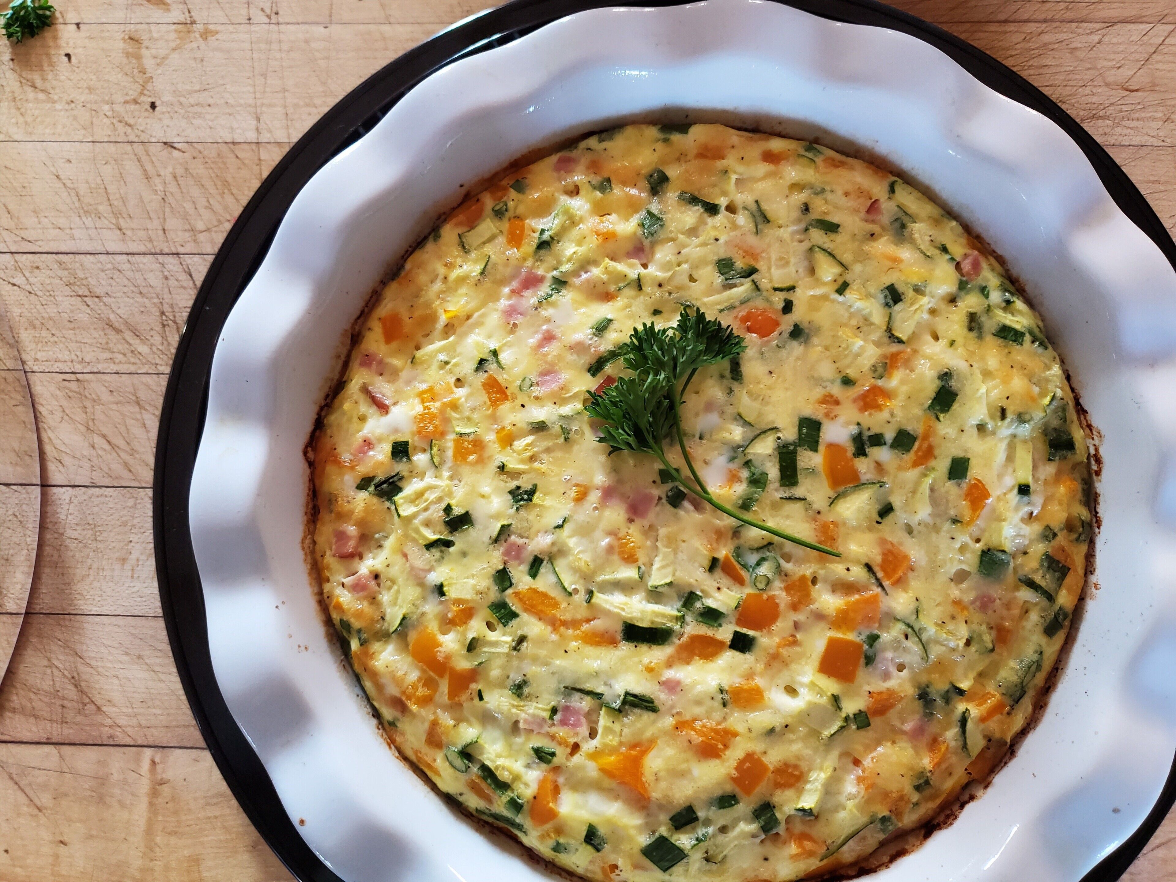 A dish with vegetables and cheese in a white bowl with a black rim.