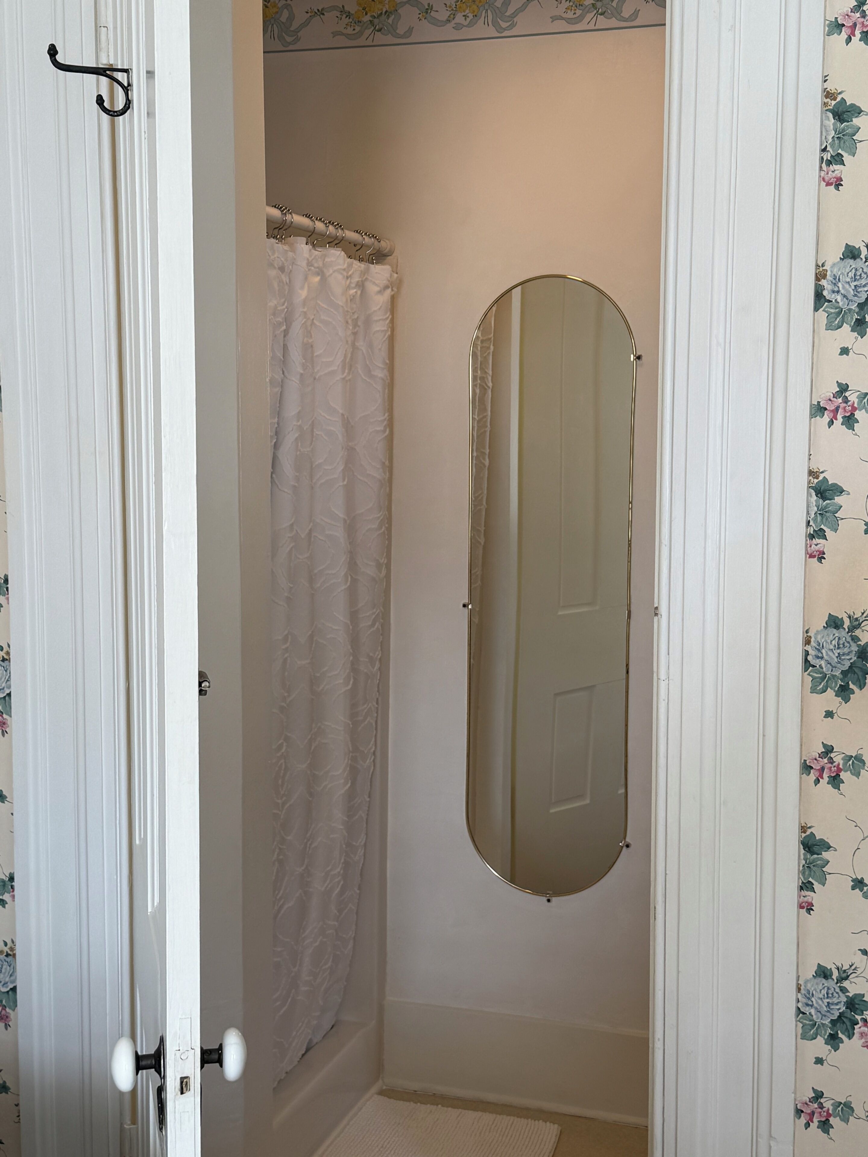 A bathroom with a shower curtain, a mirror, and a door with a handle.