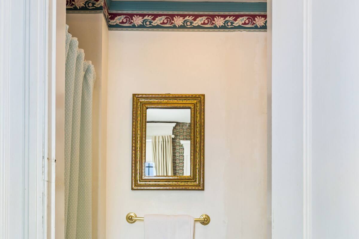 A narrow bathroom with a toilet, a towel rack, and a mirror.