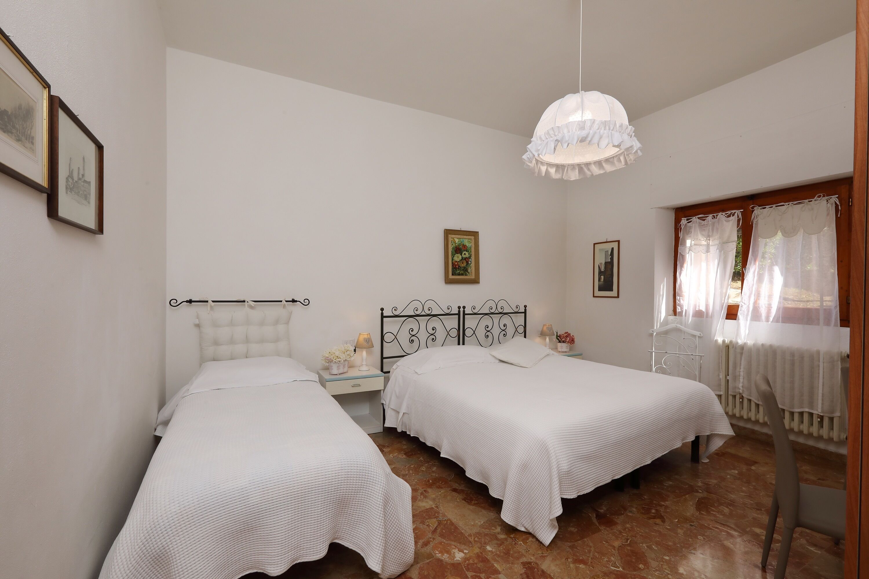 Une chambre avec deux lits, un lustre et une fenêtre avec des rideaux.
