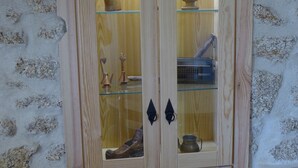 A wooden cabinet with glass doors, containing various kitchen utensils and items.