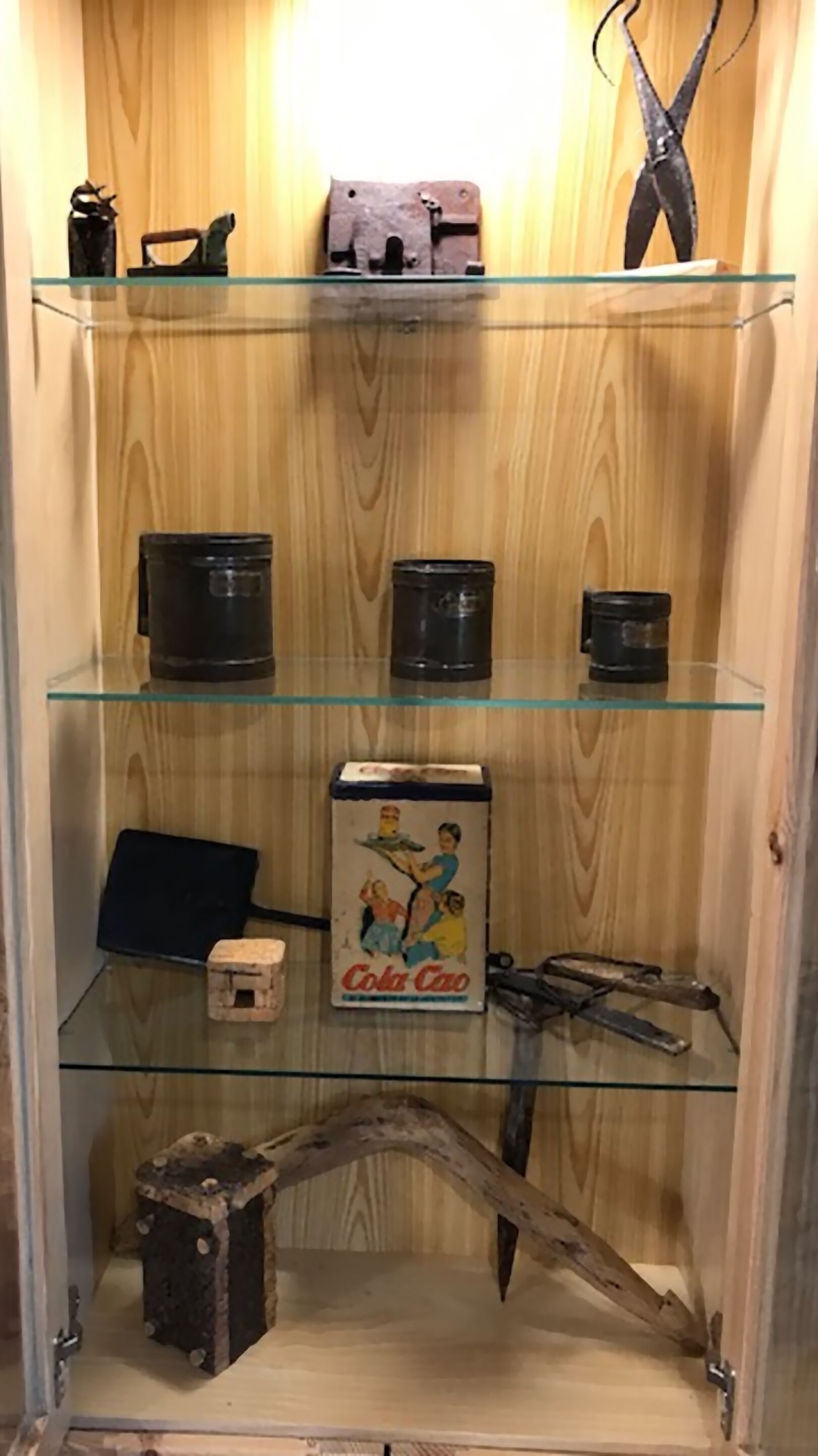 Een houten kast met drie planken, elk gevuld met verschillende spullen.