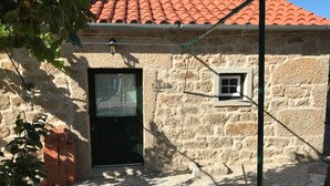 A stone building with a black door, a small window, and a tiled roof.