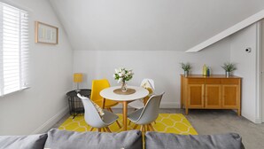 A dining area with a round table, chairs, and a yellow rug. - 84A Albany Road (Cardiff)