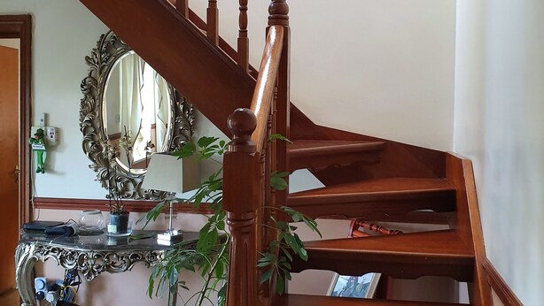 A wooden staircase with a mirror and a console table with plants. - Golden Dawn Guesthouse (Saggart)