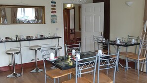 A dining area with a chandelier, a bar, and a kitchen in the background. - Golden Dawn Guesthouse (Saggart)