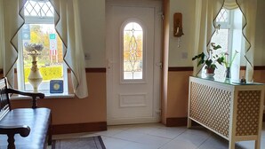 A hotel lobby with a reception desk, a bench, a patterned rug, and a door with an emergency exit sign. - Golden Dawn Guesthouse (Saggart)