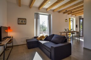 A modern living room with a sectional sofa, a dining area, and a kitchen visible through an open door.