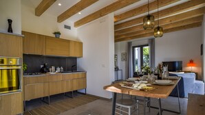 A modern kitchen with wooden cabinets, a central island, and a dining area with a table and chairs.