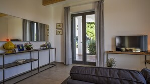 A modern living room with a sofa, a TV, a console table with decorative items, and a sliding glass door leading to an outdoor area.