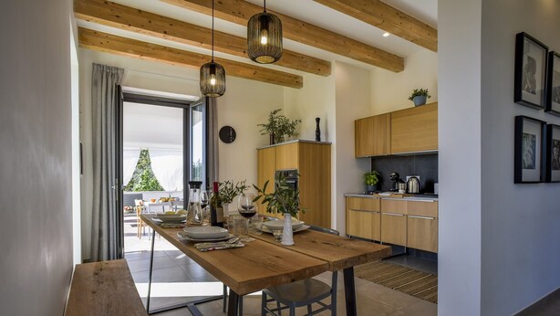 A modern kitchen with wooden cabinets, a dining table set for four, and pendant lighting.