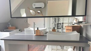 Une salle de bain moderne avec un grand miroir, deux lavabos et un plancher en bois.