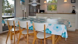 A dining area with a table covered by a blue and white floral tablecloth, surrounded by wooden chairs. - Awesome home in Strandby with kitchen (Strandby)