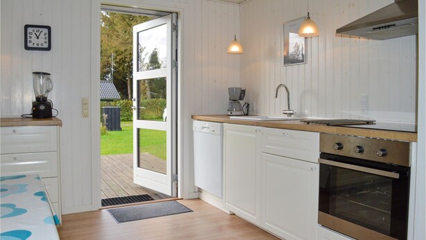 A modern kitchen with white cabinets, a wooden countertop, a built-in oven, and a coffee maker. - Awesome home in Strandby with kitchen (Strandby)