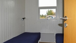 A small, single-room cabin with two single beds, a window, and a door. - Awesome home in Strandby with kitchen (Strandby)