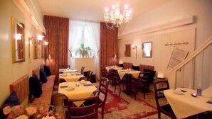 A hotel dining area with multiple tables and chairs, a chandelier, and a red carpet. - Hotel Garni Frankfurt (Frankfurt)