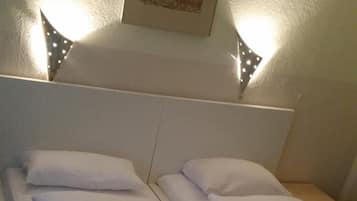 Ein Doppelbett mit weißer Bettwäsche und einem Kopfteil, ein kleiner Nachttisch und ein gerahmtes Bild an der Wand.