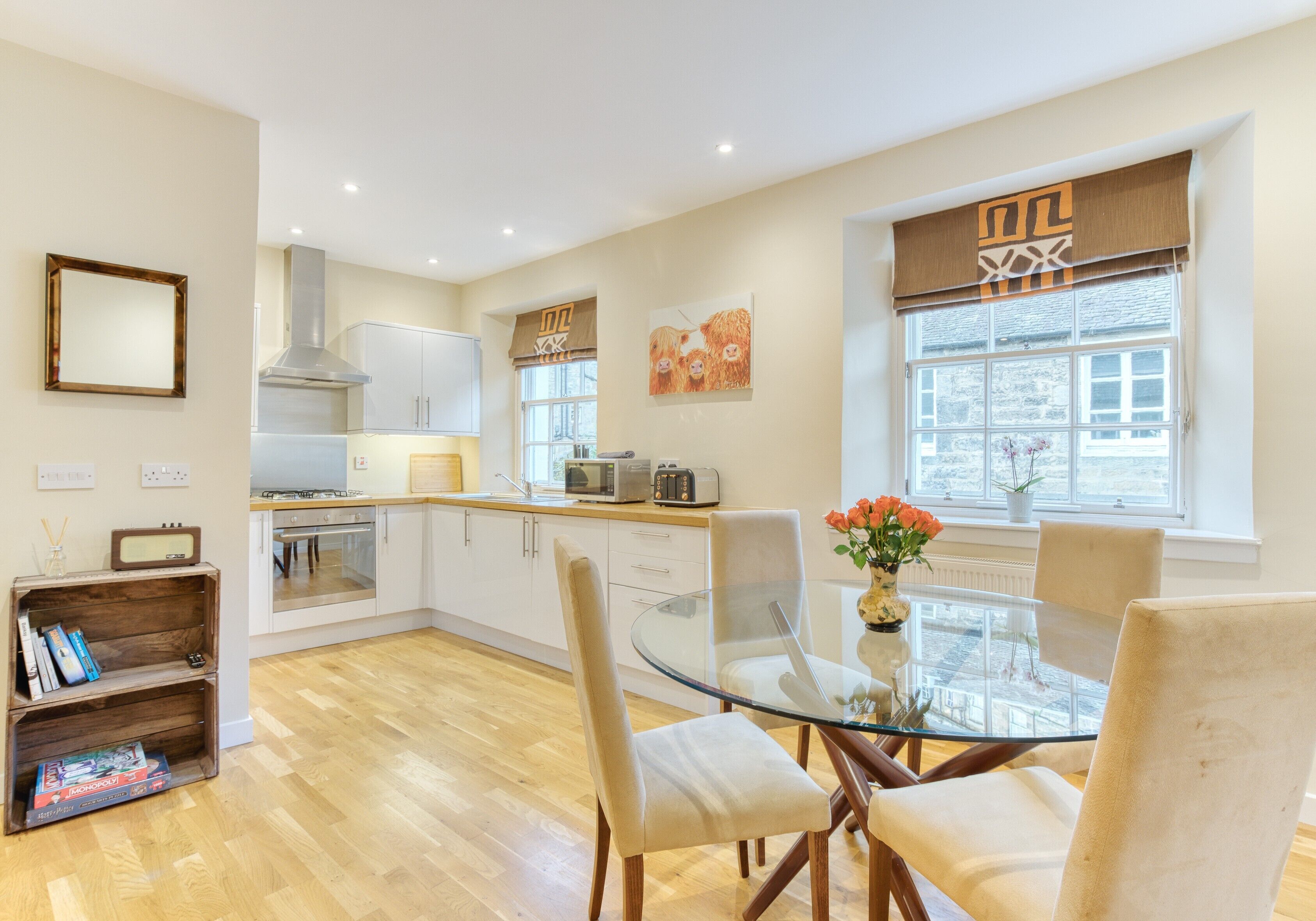 A modern kitchen with white cabinets, a central island, and a dining area with a glass table and chairs.