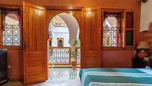 A room with a bed, a potted plant, and a view of an outdoor courtyard. - Riad Villa Sidi Baba (Marrakech)