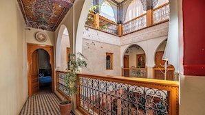 A multi-level interior with ornate iron railings, checkered flooring, and a ceiling with intricate designs. - Riad Villa Sidi Baba (Marrakech)