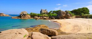 A coastal landscape with a large estate, clear waters, and rocky formations. - COTTAGE MERLIN 3* SPA Privatif et Sauna (Trélévern)
