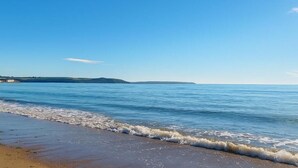 A beach with clear blue water and a sandy shore.