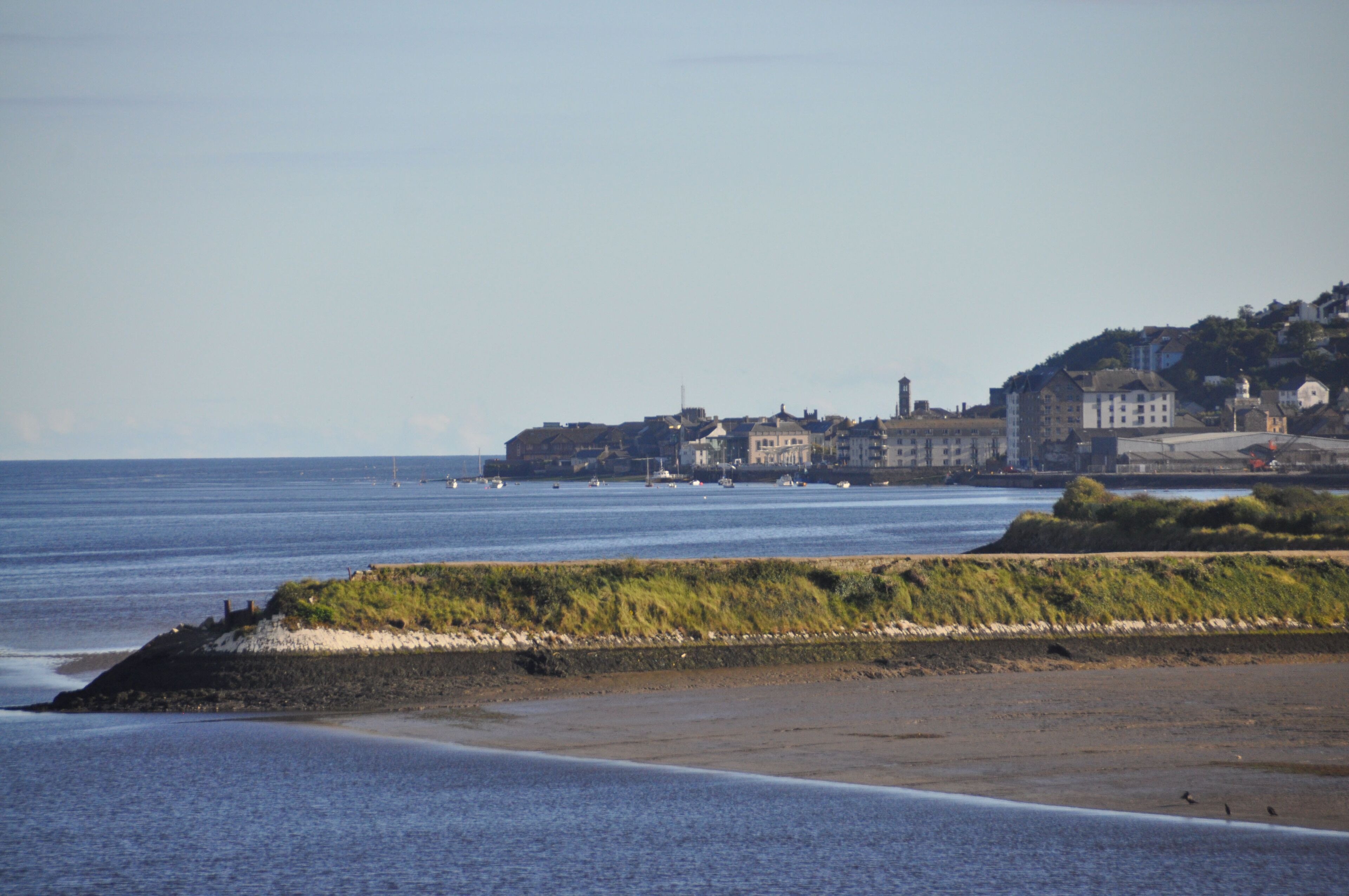 Une ville côtière avec des bâtiments qui bordent la plage, une étendue de sable et une mer calme.