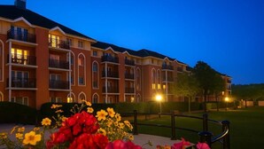 A multi-story hotel with balconies and a well-lit entrance.