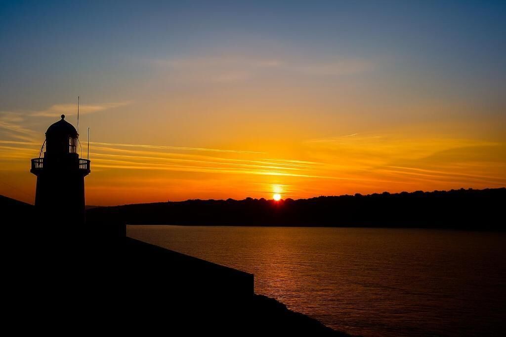 Silueta de un faro contra un atardecer.