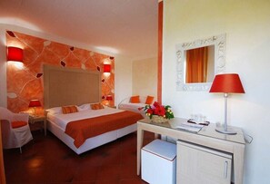 Une chambre d’hôtel comprenant un lit, des tables de chevet, un bureau avec une lampe, une chaise et un miroir.