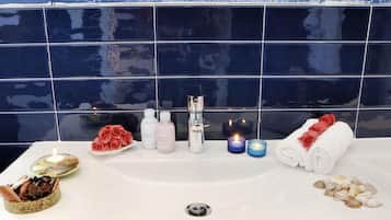 Casa de banho com uma pia branca, um espelho e uma parede revestida de azulejos azuis.