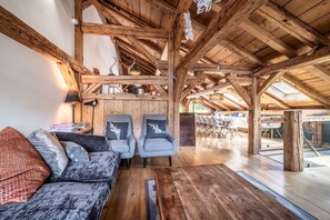 Un acogedor espacio tipo loft con vigas de madera a la vista, un sofá con cojines estampados y una zona de comedor con sillas modernas.