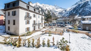 Un edificio coperto di neve con balconi e un'area di parcheggio davanti.