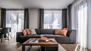 Un soggiorno moderno con un divano componibile, un tavolino in legno e vista sulla città attraverso ampie finestre.