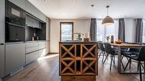 Una cucina moderna con elettrodomestici integrati, un'isola in legno e un'area pranzo con un lampadario.
