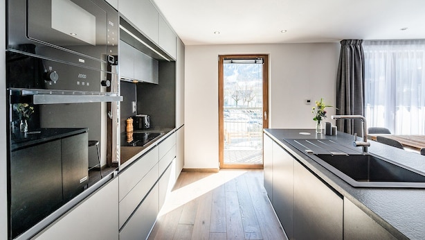 Una cucina moderna con forno integrato, lavello e finestra vista esterna.