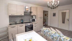 Una cocina moderna con microondas, hervidor y estufa, una mesa de comedor con mantel floreado y una araña.