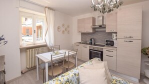 Una cocina moderna con zona de comedor, que incluye un radiador, una mesa con sillas, un microondas y armarios.