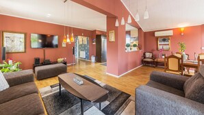 Un salon moderne doté d’un téléviseur à écran plat, de sièges confortables et d’un coin repas avec une table et des chaises.