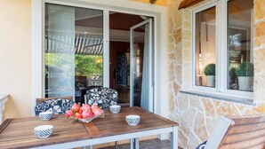Un coin repas avec une table en bois, des coussins aux motifs noir et blanc et un panier de fruits.