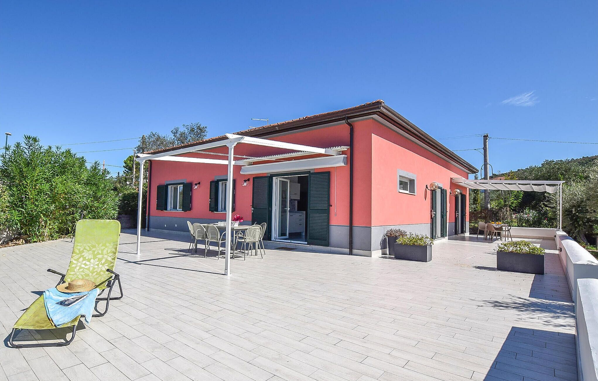 A red building with a covered patio area, outdoor seating, and a poolside chair.