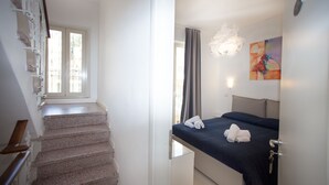 A hotel room with a bed, a painting on the wall, a staircase, and a door. - Casa Don Micio (Taormina)