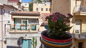 A potted plant with flowers in a colorful pot on a balcony. - Casa Don Micio (Taormina)