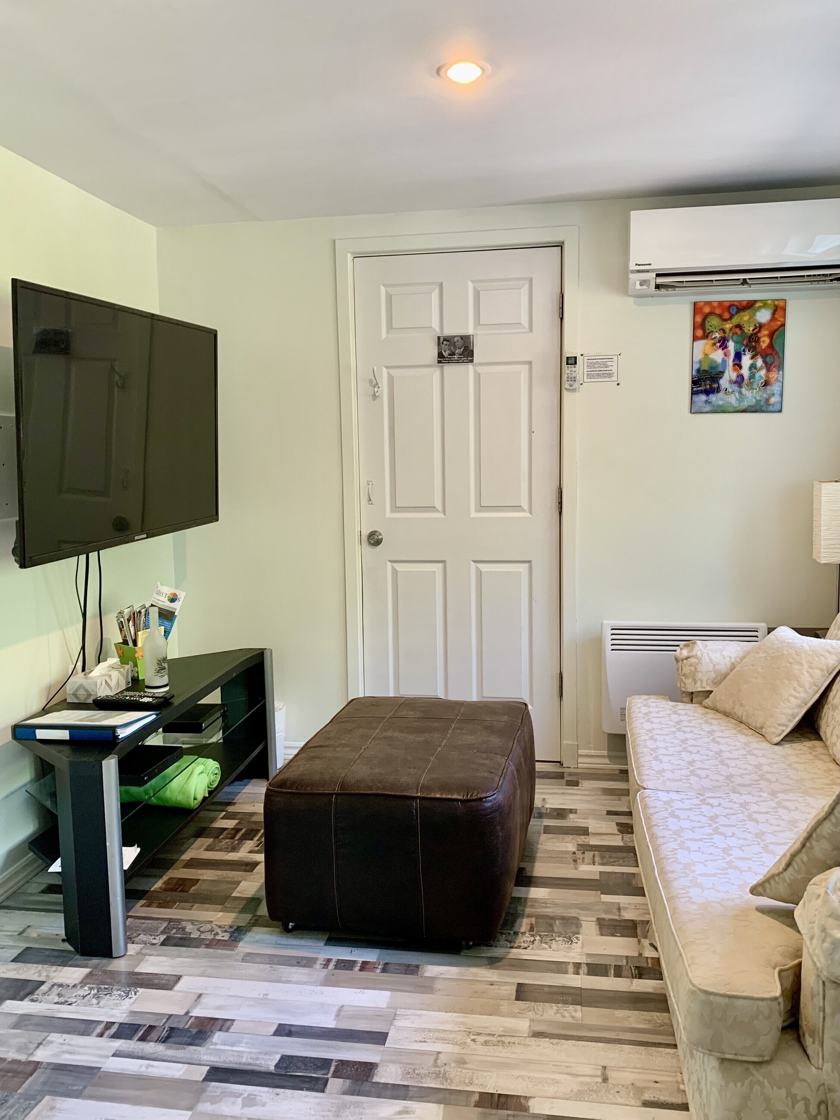 A living room with a flat-screen TV, a sofa, a coffee table, and a patterned floor.