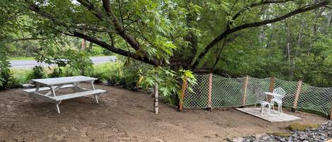 Un área de picnic con una mesa y sillas, rodeada por una cerca y árboles.