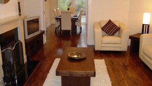 Una sala de estar con chimenea, un sofá, una mesa de centro y un comedor al fondo.