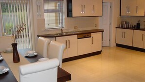 Una cocina moderna con armarios blancos, encimera de madera y un comedor con mesa y sillas.
